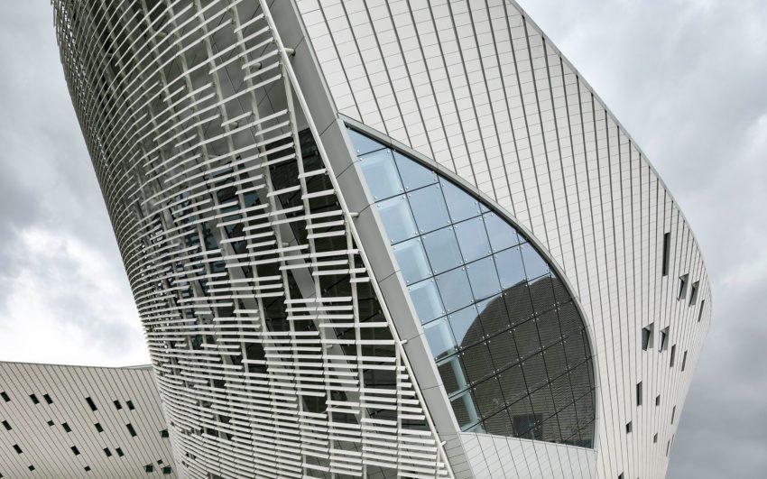The facades are entirely clad with ceramic elements. The glazed façade of the venue foyers called the “Curved Galleries” are shaded on the exterior by white ceramic baguettes with a lens shaped profile